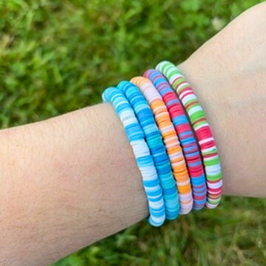 Colorful striped bracelets on a wrist with a grassy background