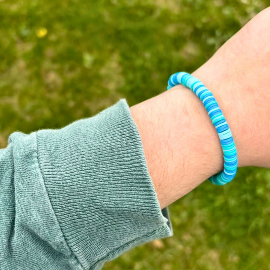 Person wearing a blue bracelet on a grassy background